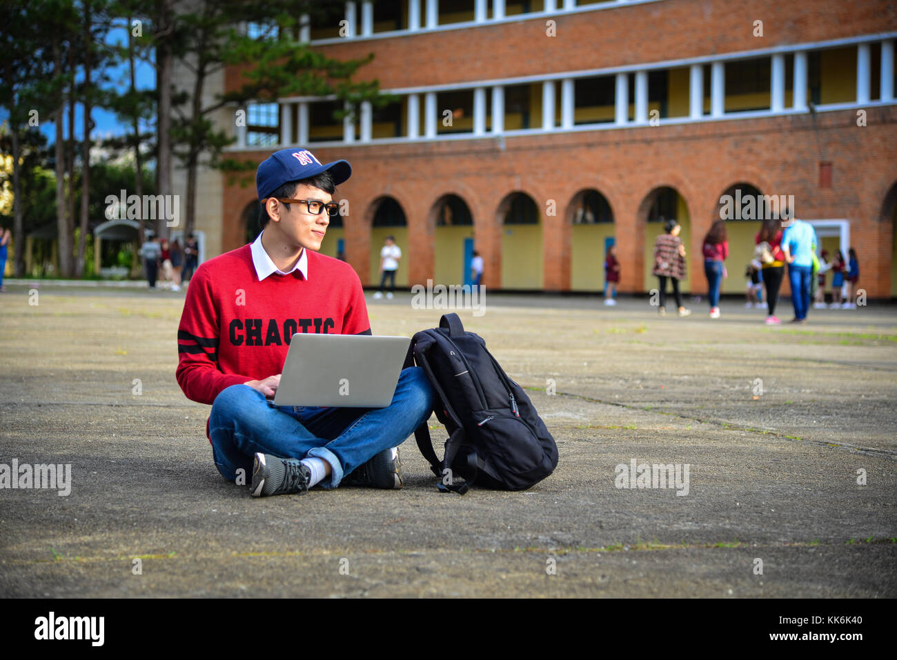 Young Asian man sitting working with laptop in college building Stock ...