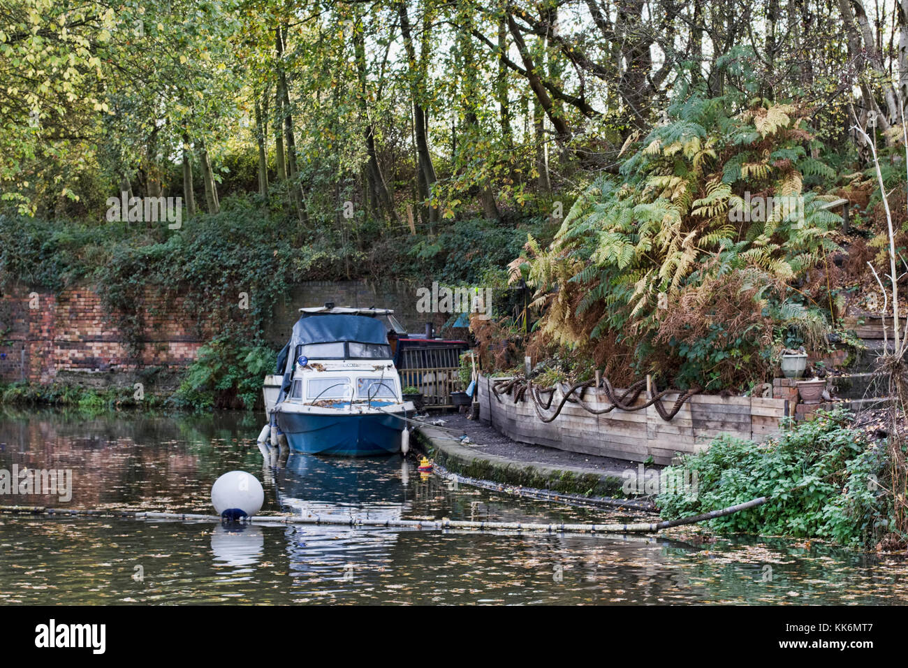 a small boat moored in a small wharf on the english canals in the autumn Stock Photo