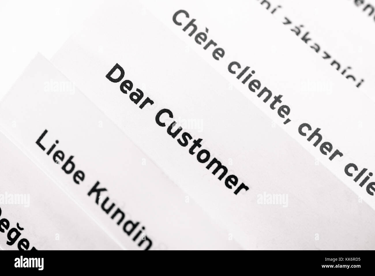 Pages with words Dear Customer in different languages. Close-up Stock ...
