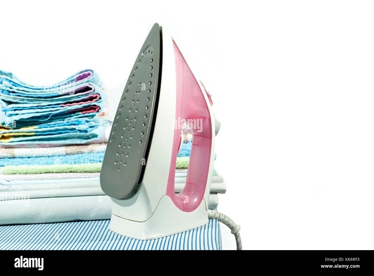 pink electric iron and a stack of ironed clothes on an ironing board on a  white background Stock Photo - Alamy