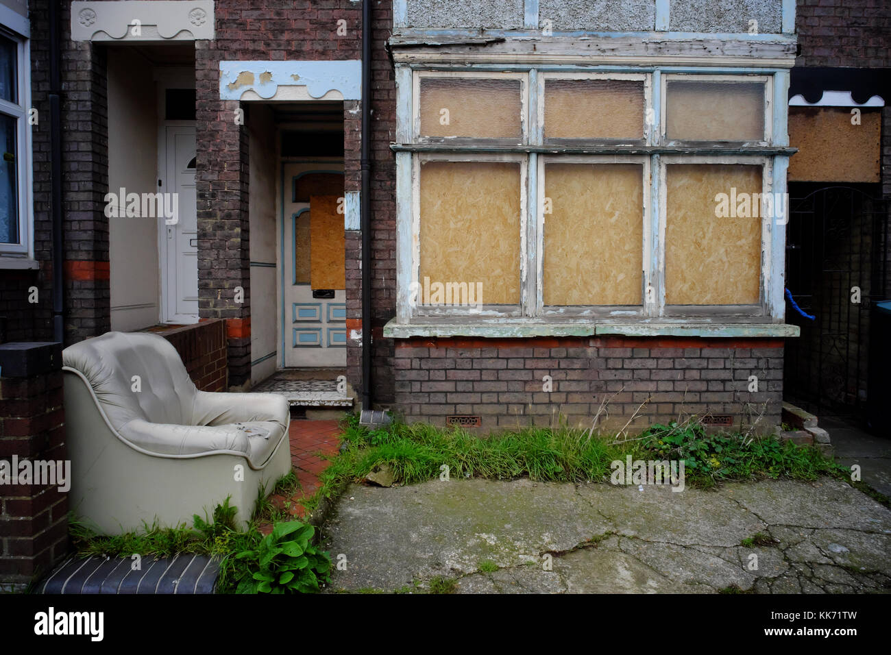 Boarded up house with old sofa left outside in Luton, Bedfordshire, England Stock Photo