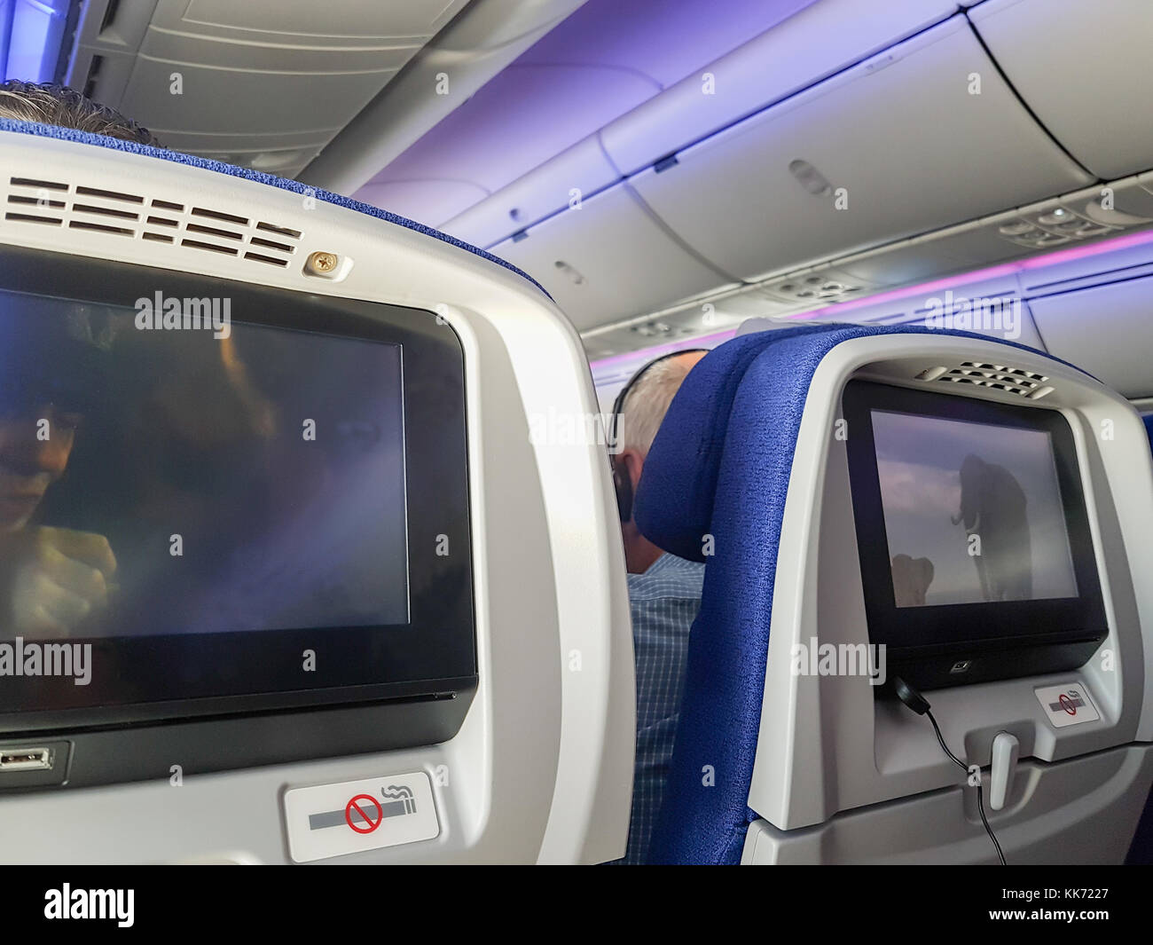 No smoking signs and screens on back of passenger airplane seats from mobile phone Stock Photo