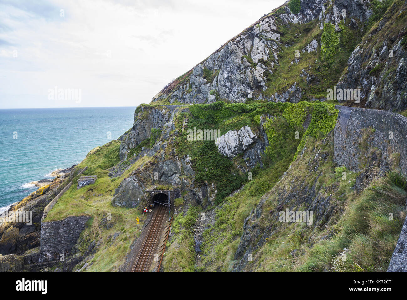Railway through stone rocks mountain at Irish seacoast. Bray, Greystone Stock Photo