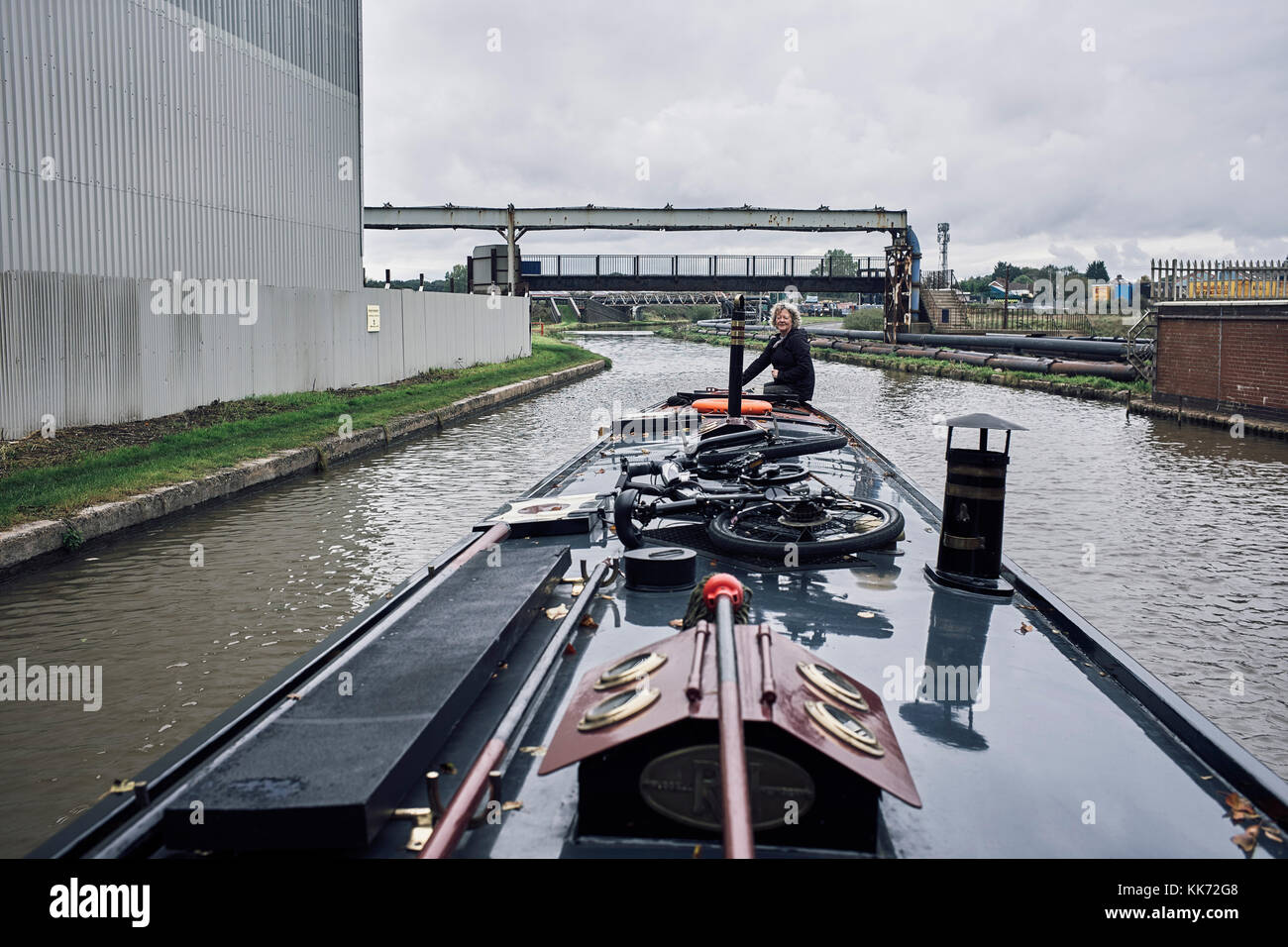 Steering a narrowboat through chemical works at Northwich on the Trent and Mersey canal Stock Photo
