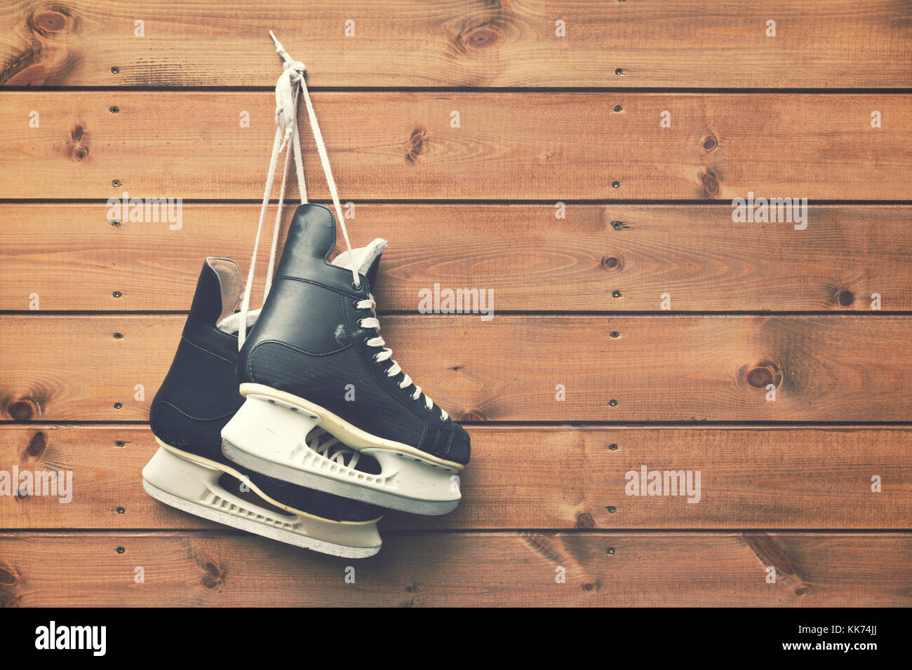 ice hockey skates hanging on nail on wooden plank background Stock Photo
