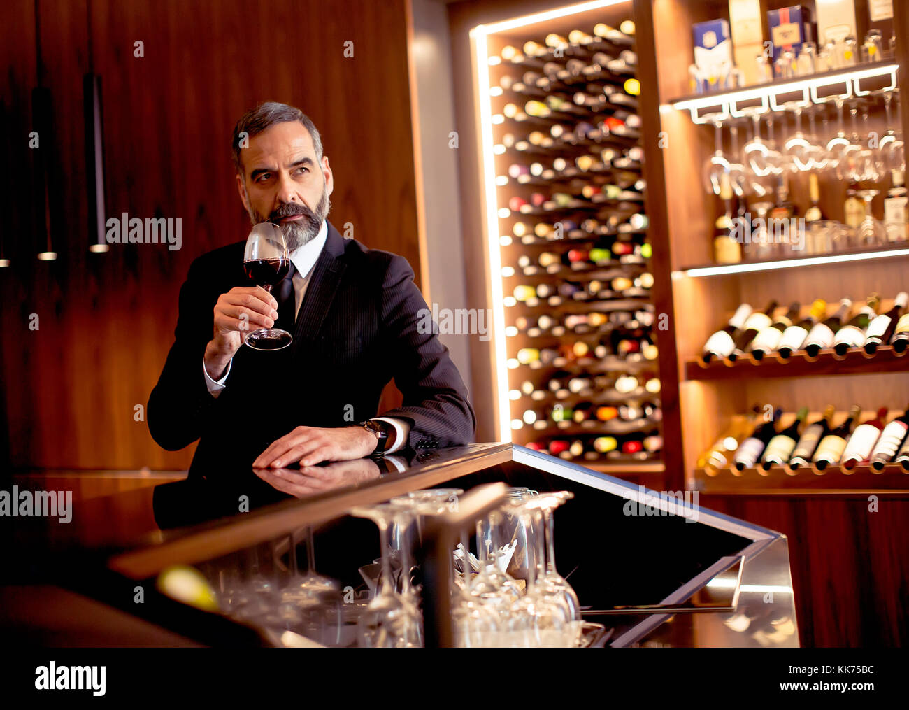 Handsome elegant businessman drinking red wine in bar Stock Photo - Alamy