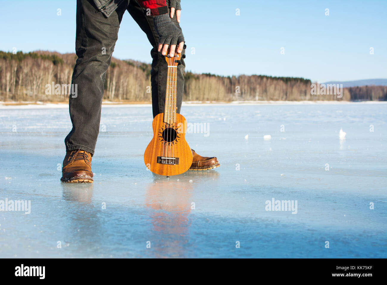 Man with ukelele standing on a frozen lake Stock Photo