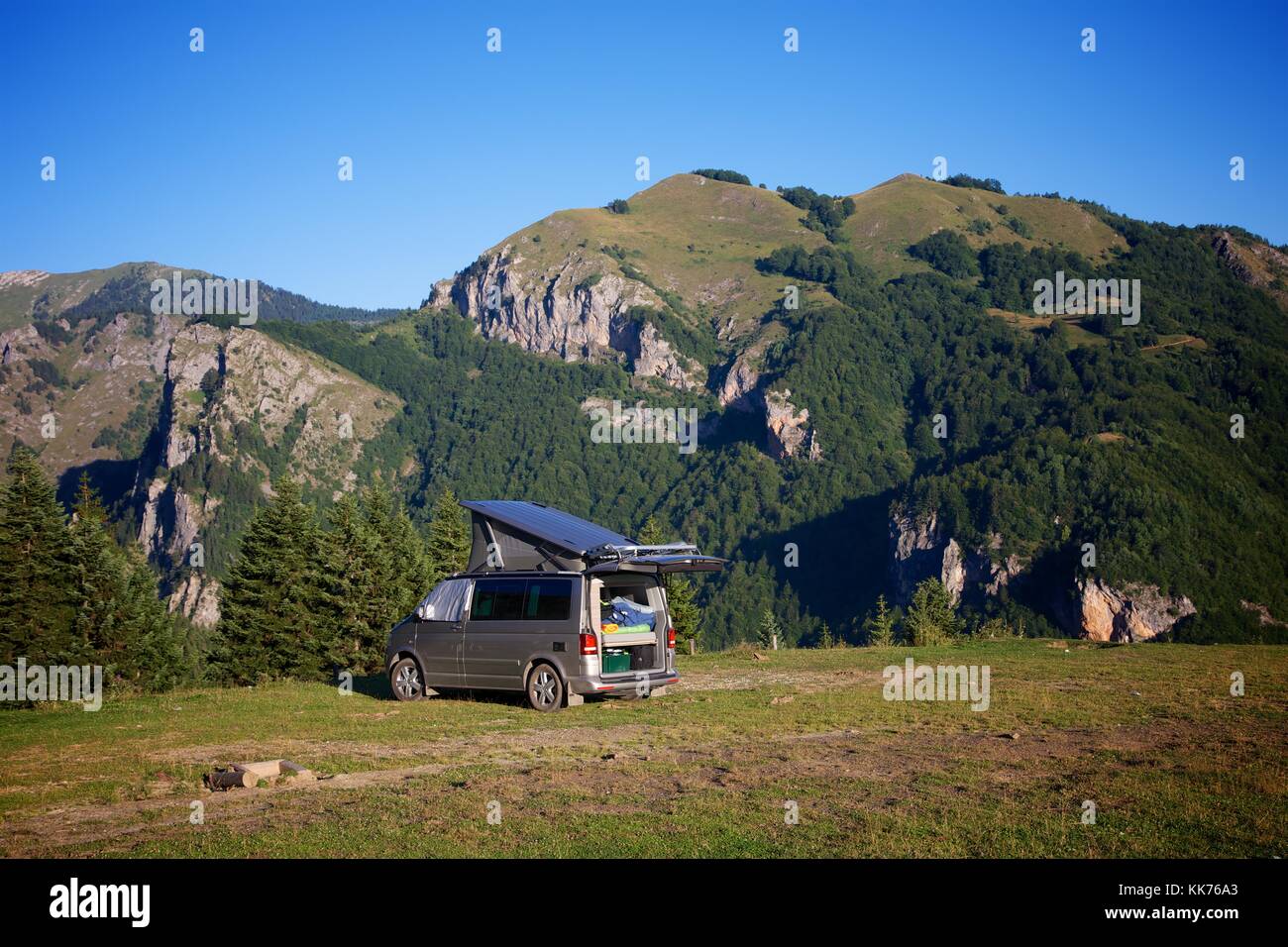 A female camper returning to her motorhome in a field high on a hill above the Rugova Valley Kosovo on a bright sunny day. Stock Photo