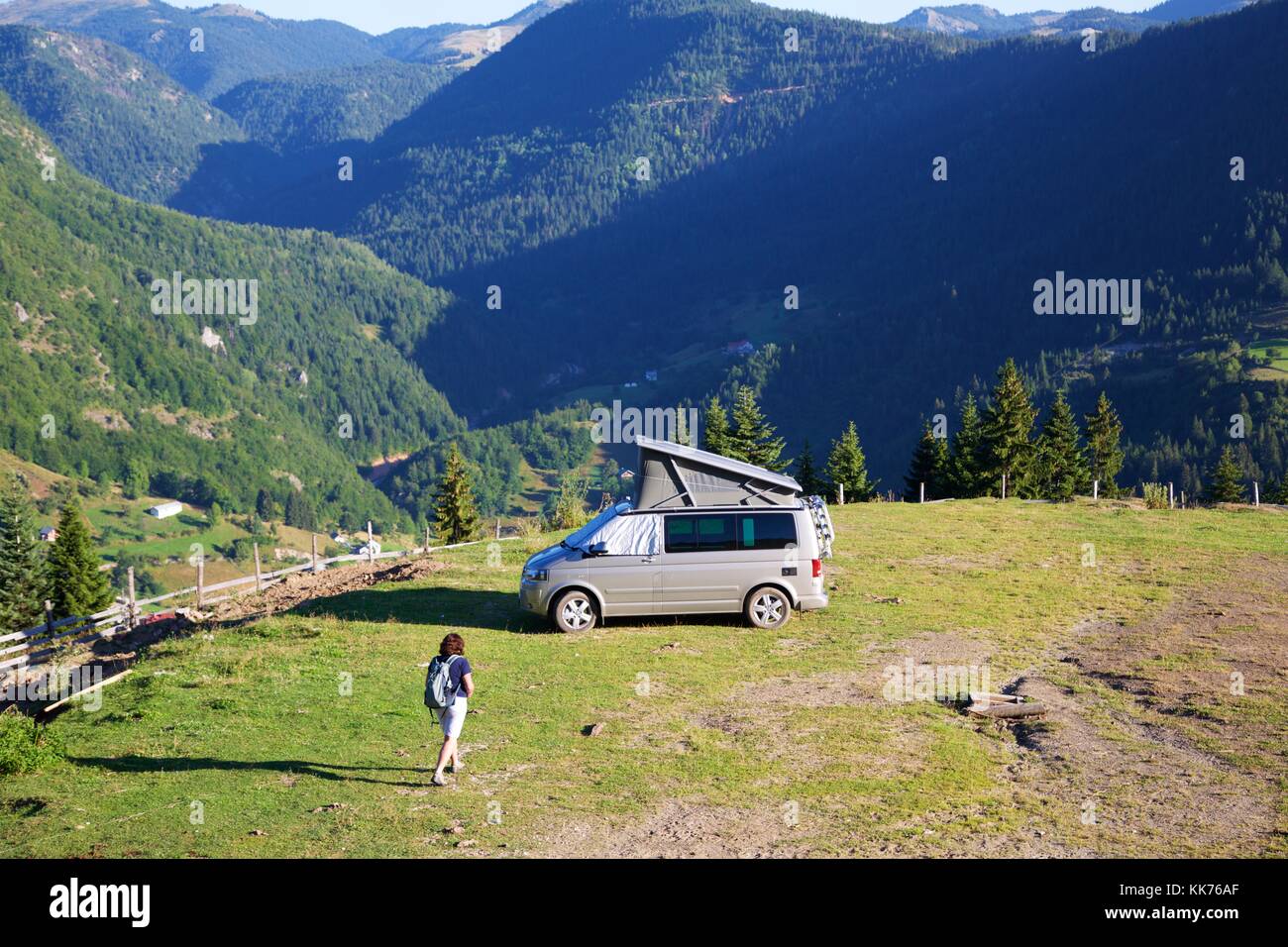 A female camper returning to her motorhome in a field high on a hill above the Rugova Valley Kosovo on a bright sunny day. Stock Photo