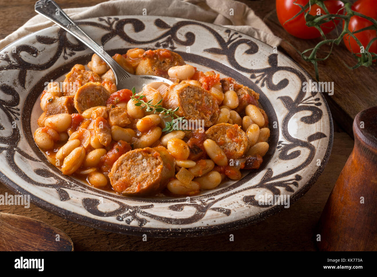 A delicious hearty cassoulet with artisanal sausage, tomato, bacon and white beans on a rustic tabletop. Stock Photo