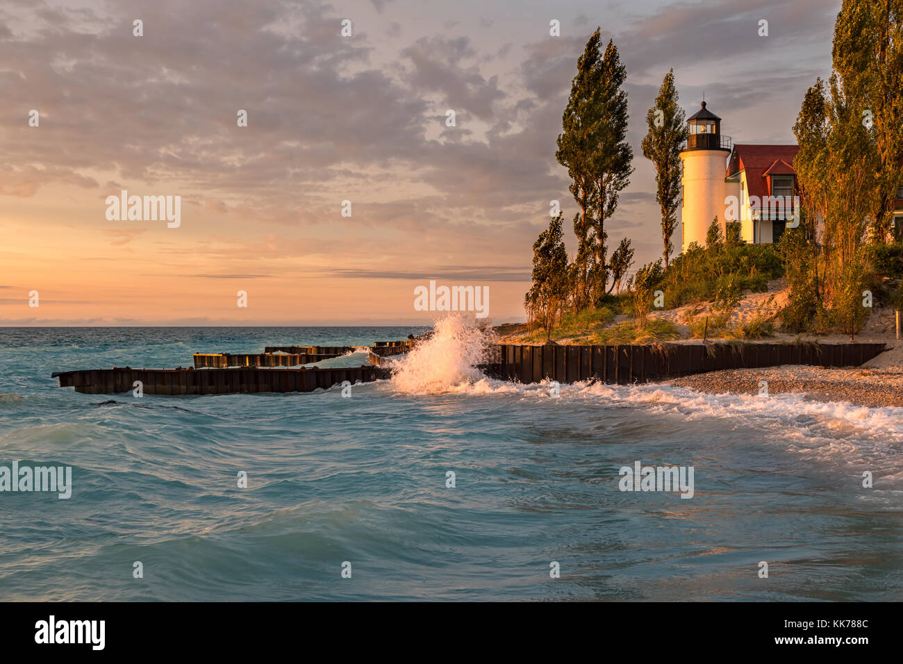 Waves crash along the Lake Michigan shore in front of Point Betsie Lighthouse, during sunset Stock Photo