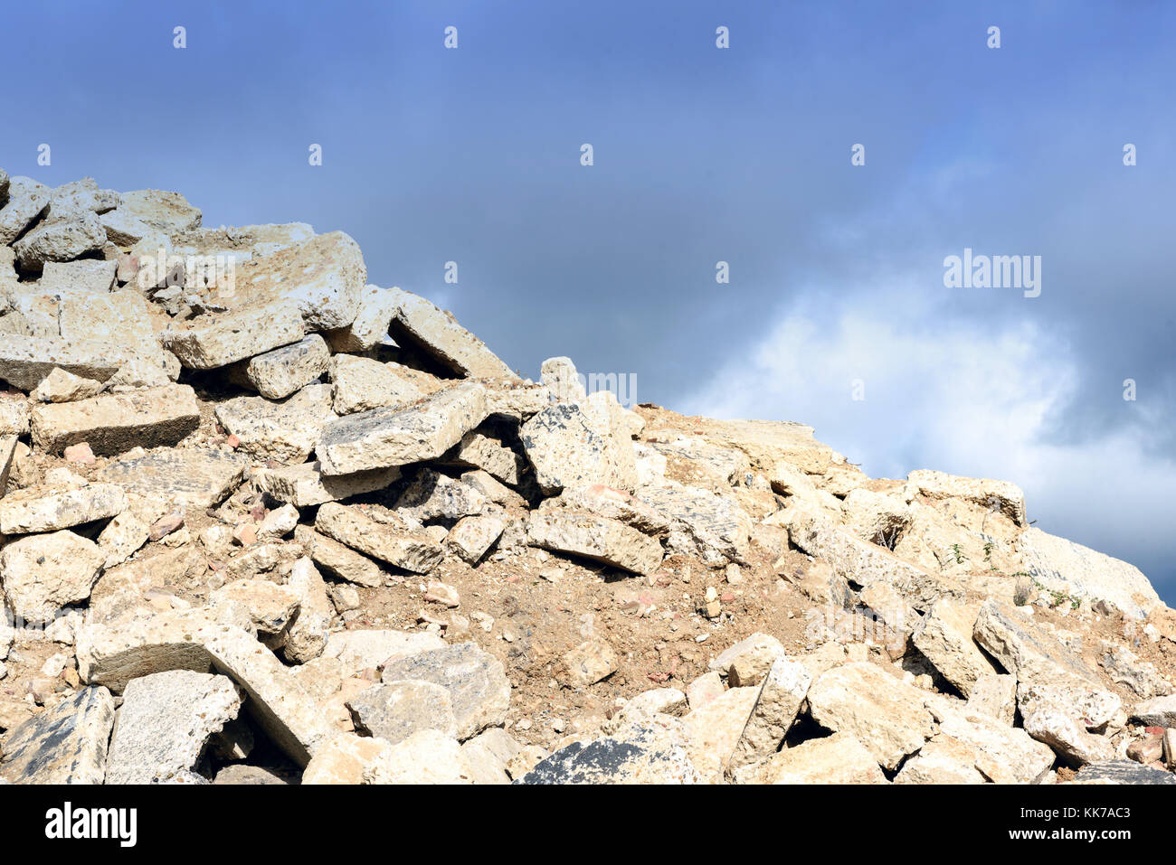 Broken pile of hardcore cement rubble stacked in a loose pile with a ...