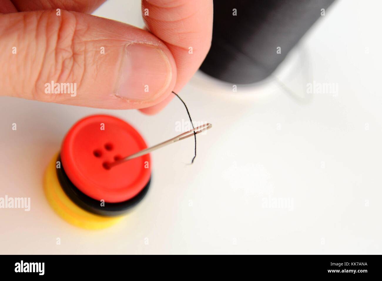 hand threading a needle with black thread Stock Photo Alamy