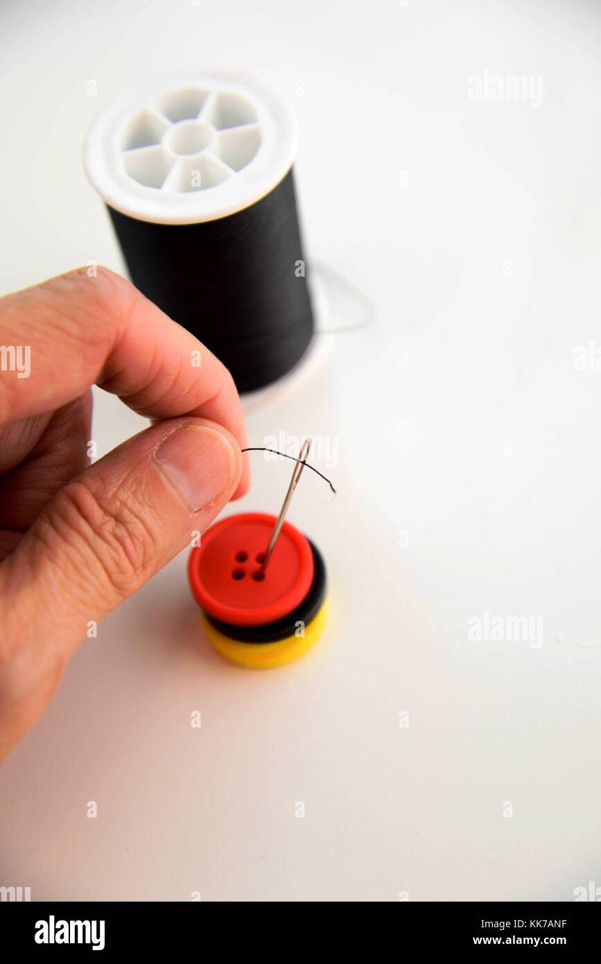 hand threading a needle with black thread Stock Photo Alamy