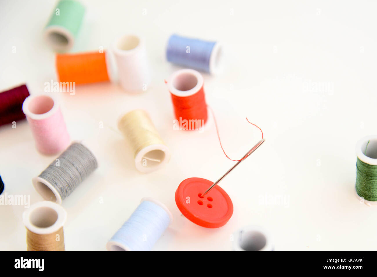 red thread through needle eye and red button with multi colored thread ...