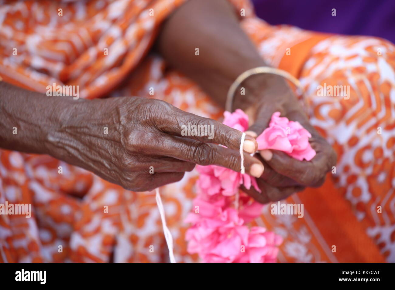 indische Frau flechten mit Schnur Blumen zu einer Girlande für den Tempel - Indian woman braid with string flowers to a garland for the temple Stock Photo