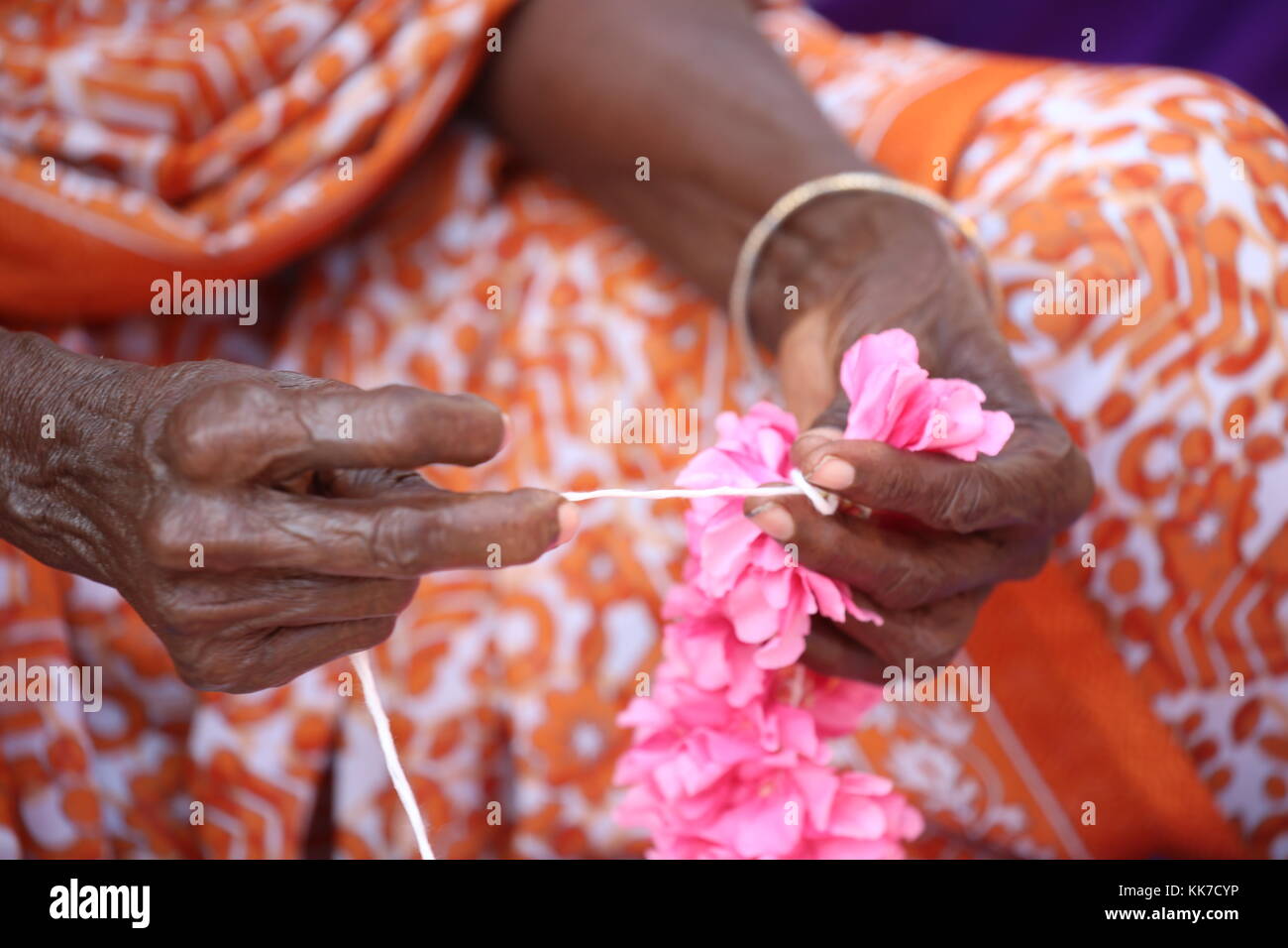indische Frau flechten mit Schnur Blumen zu einer Girlande für den Tempel - Indian woman braid with string flowers to a garland for the temple Stock Photo