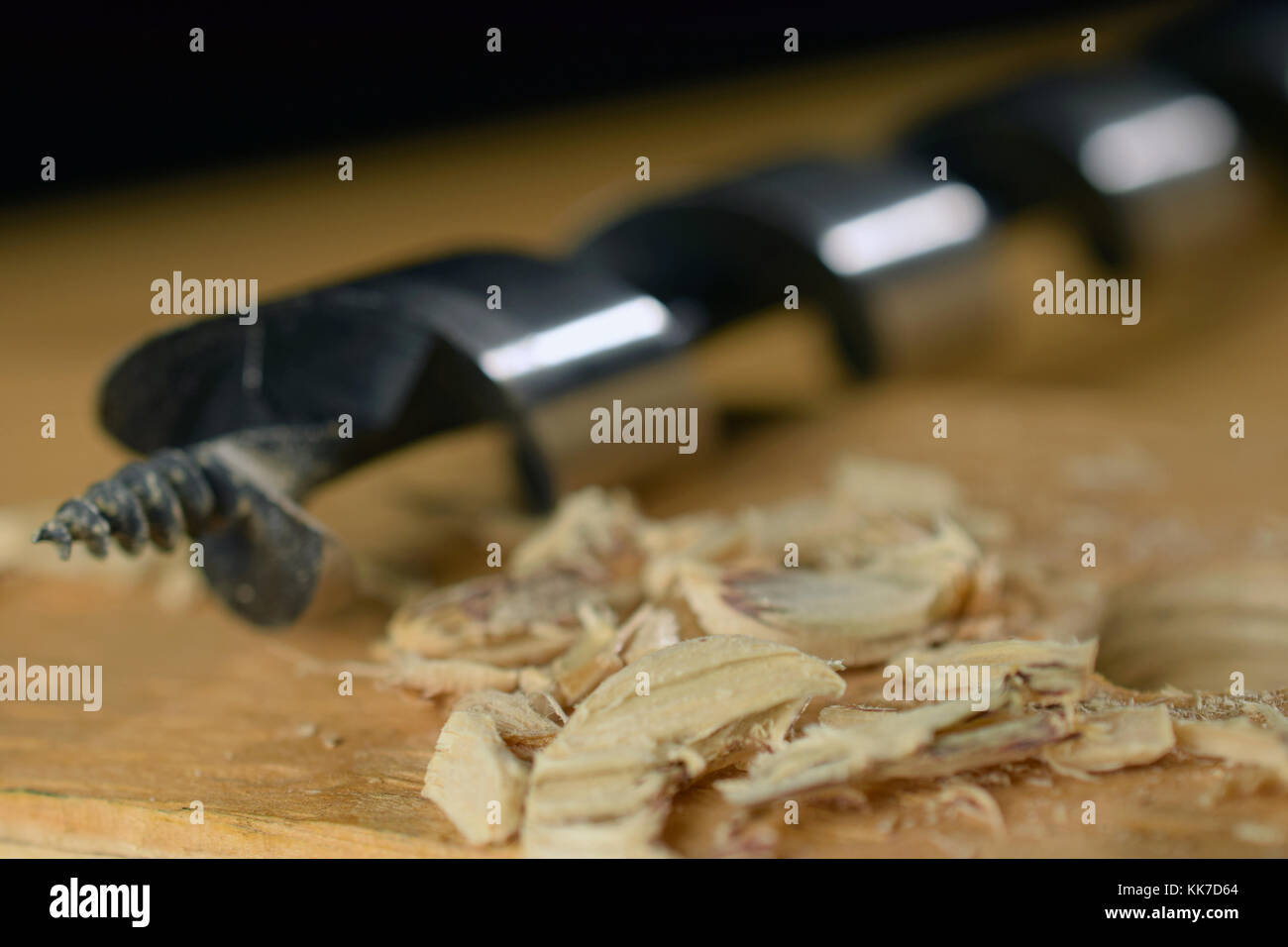 Shavings and wood drill bit on wooden board as woodworking background image. Selective focus Stock Photo