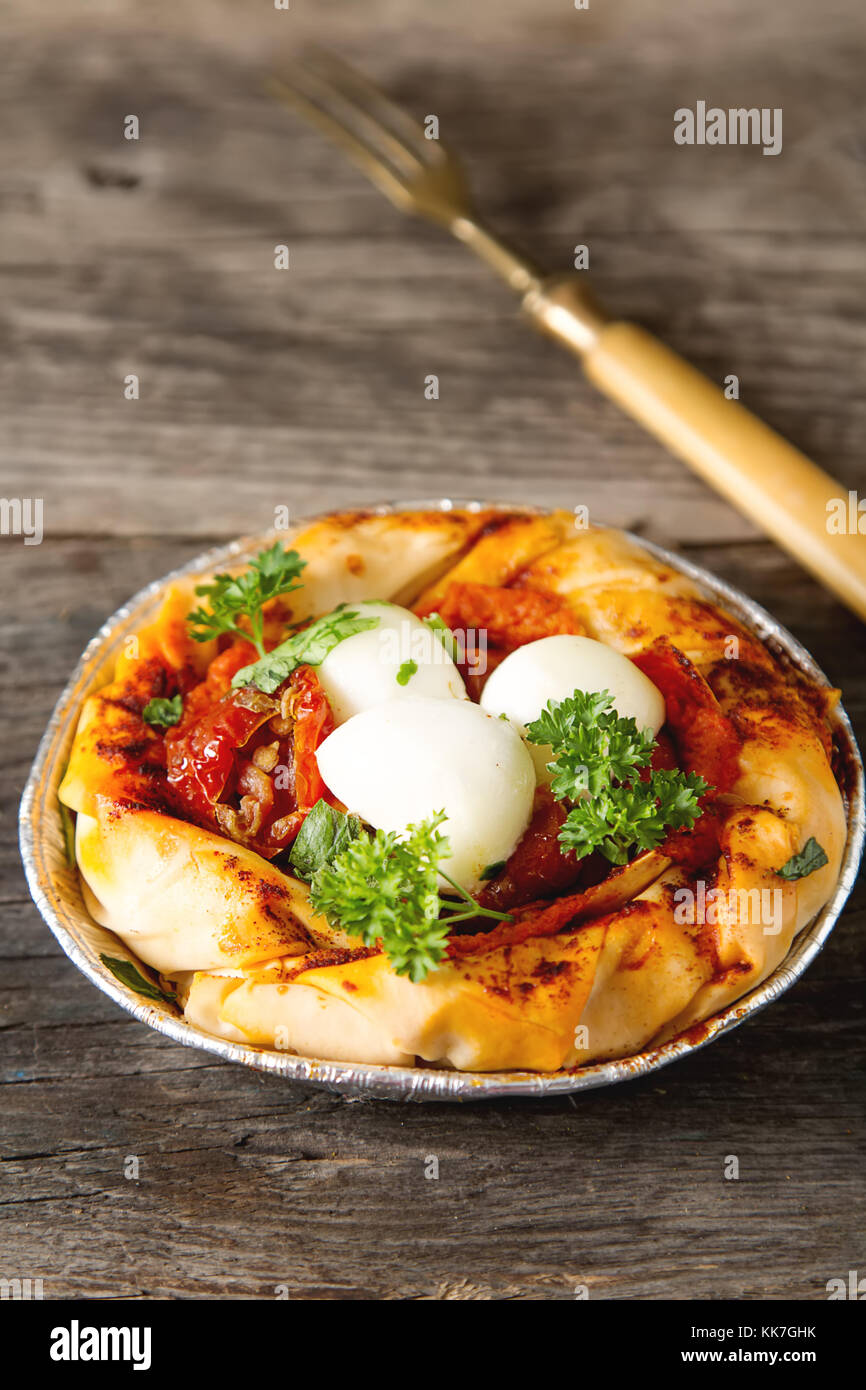 Pie in the oriental style. Filo pastry with tomato and mozzarella. Dark