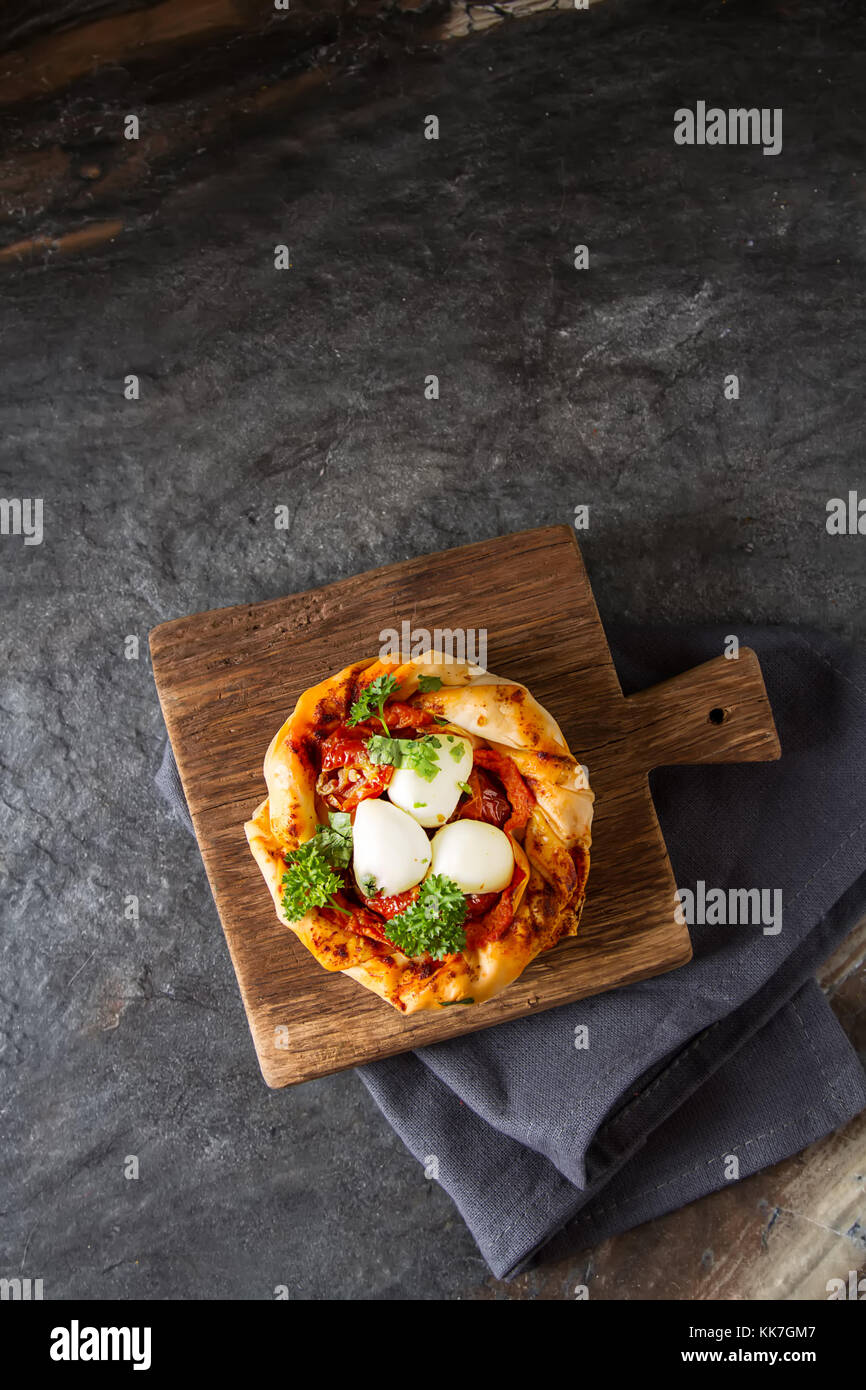 Pie in the oriental style. Filo pastry with tomato and mozzarella. Dark