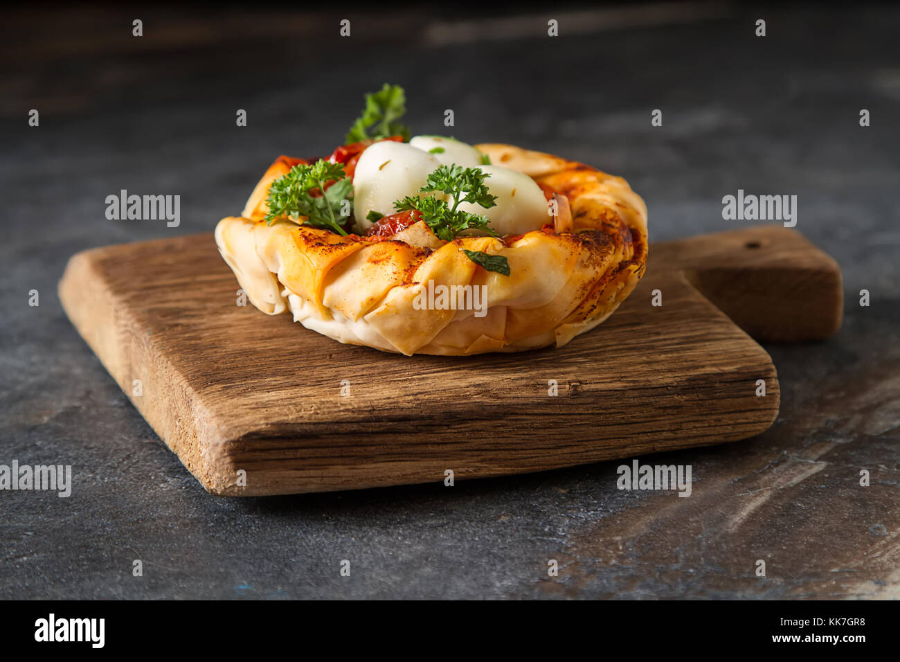Pie in the oriental style. Filo pastry with tomato and mozzarella. Dark