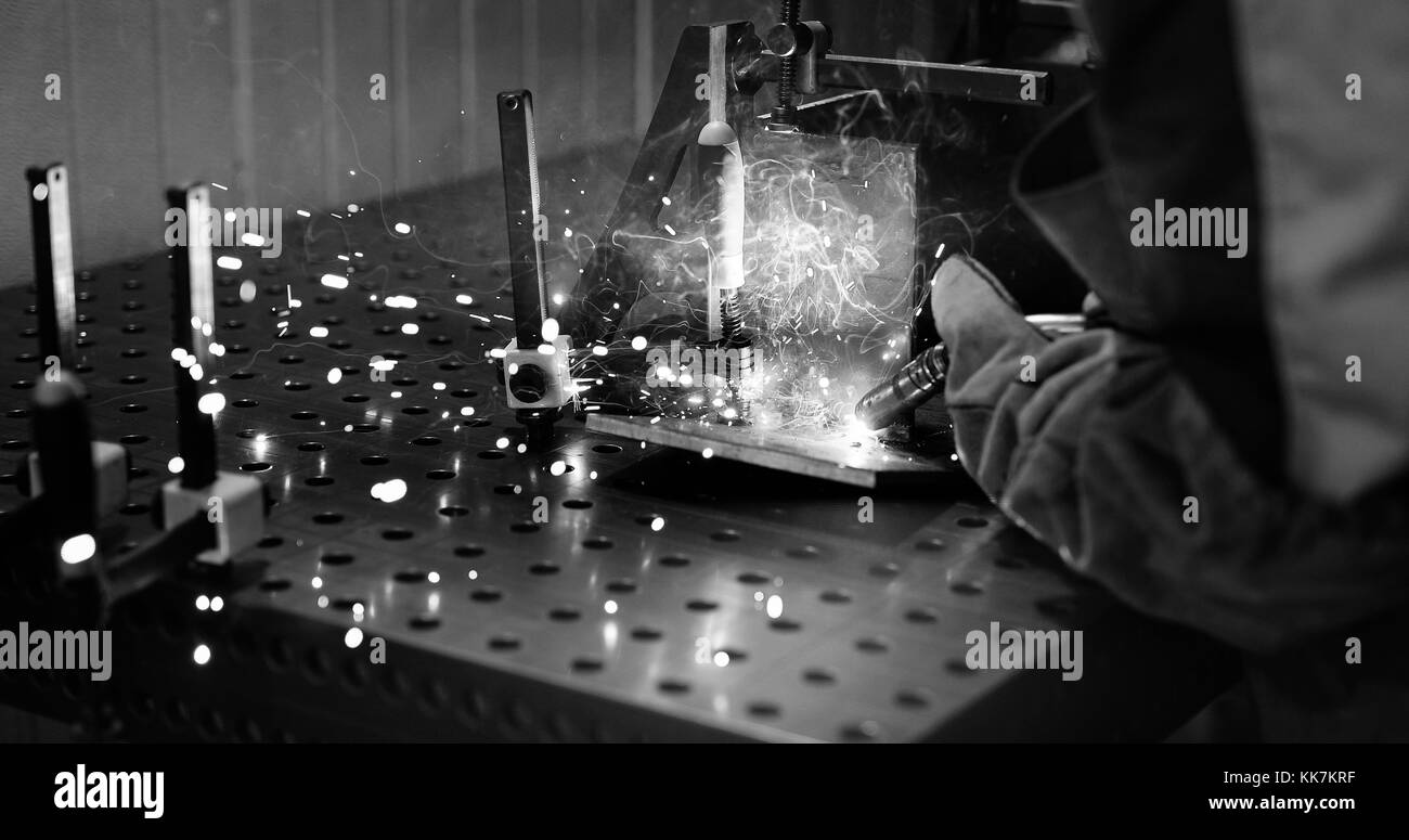 Worker cutting metalsheet by acetylene torch with bright sparks Stock Photo