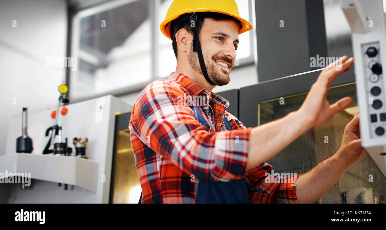 Industry Worker entering data in CNC machine at factory Stock Photo