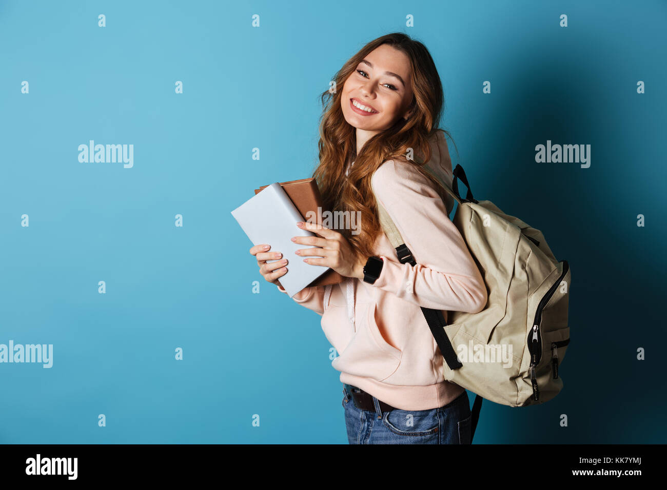 Portrait of a smiling cheery girl student with backpack holding books ...