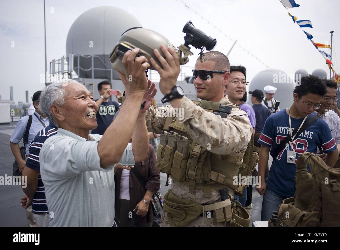 Staff Sgt Max Veliz, a Marine assigned to Fleet Anti-Terrorism Security Team FAST Company Pacific, 3rd Platoon, puts a helmet on a visitor during an open ship tour aboard the US 7th Fleet flagship USS Blue Ridge LCC 19 in Tokyo, Japan, 2012. Image courtesy Mass Communication Specialist 3rd Class Fidel C. Hart/US Navy. Stock Photo