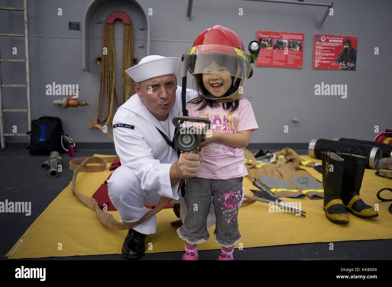 Damage Controlman 1st Class Nathan Alberti, a Sailor aboard the US 7th Fleet flagship USS Blue Ridge LCC 19, gives a fire fighting demonstration to a child during an open ship tour in Tokyo, Japan, 2012. Image courtesy Mass Communication Specialist 3rd Class Fidel C. Hart/US Navy. Stock Photo