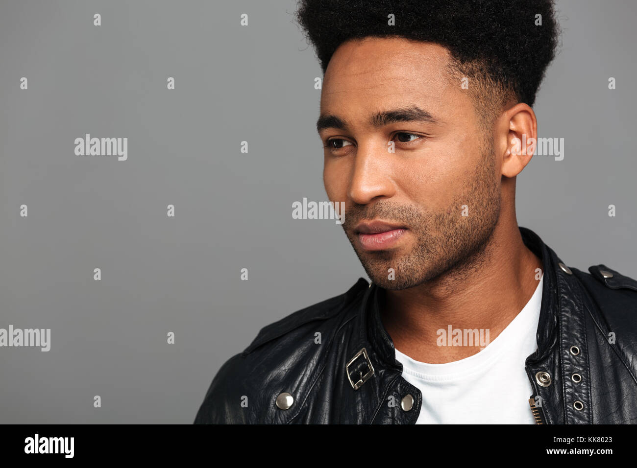 Close-up photo of serious young afro american guy with stylish haircut looking aside, isolated on gray background Stock Photo