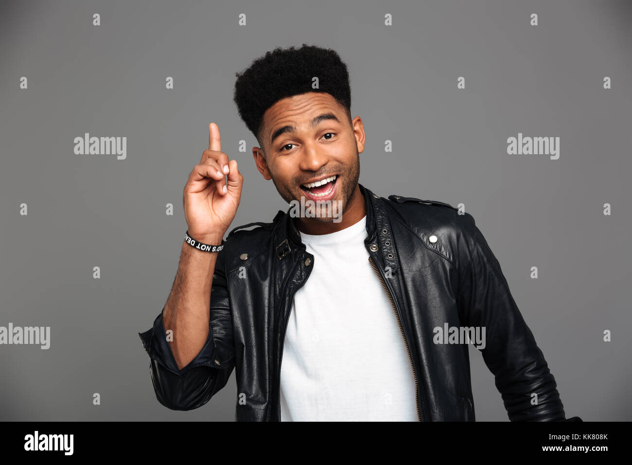 Cheerful afro american stylish man pointing with finger upward, looking at camera, isolated over gray background Stock Photo