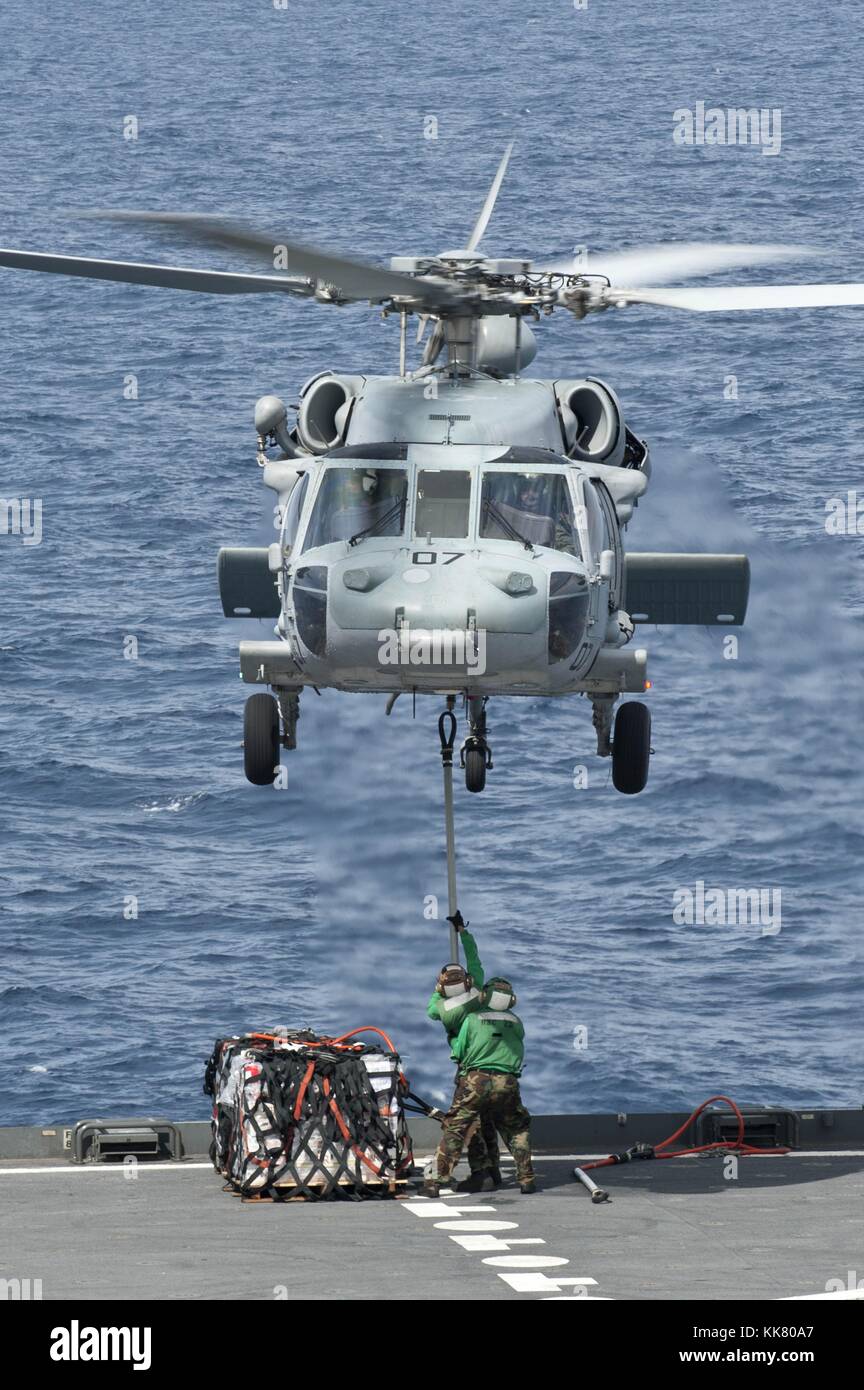 A MH-60S Sea Hawk helicopter from the Island Knights of Helicopter Sea Combat Squadron HSC 25 lifts supplies from the fantail of the Military Sealift Command dry cargo and ammunition ship USNS Amelia Earhart T-AKE 6 before delivering them to the aircraft carrier USS George Washington CVN 73 during a replenishment at sea, Pacific Ocean, 2012. Image courtesy Mass Communication Specialist 3rd Class Paul Kelly/US Navy. Stock Photo