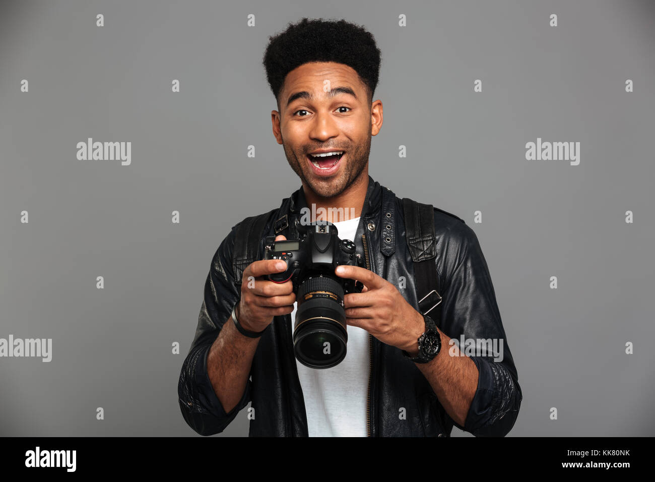 Close-up portrait of happy exited afro american man holding photocamera, isolated on gray background Stock Photo