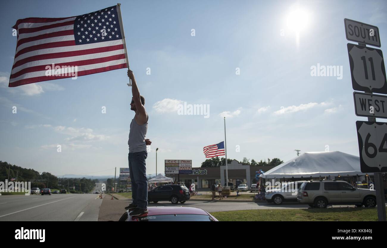 Josh Thurman, from Spring City, Tennessee, waves the American flag from the top of his car at the memorial in front of Armed Forces Recruiting Center in Chattanooga, Tennessee. Thurman had been driving from his home to the memorial everyday to wave the flag. Image courtesy Chief Mass Communication Specialist Michael D. Cole/US Navy, United States, 2015. Stock Photo