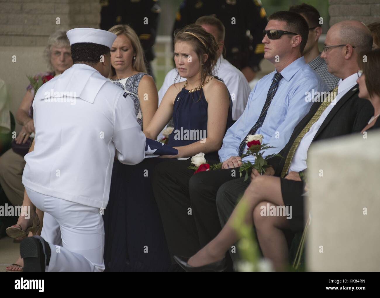 Operations Specialist 2nd Class Jose Rodriguez presents a folded American flag to Angie Smith, widow of Logistics Specialist 2nd Class Randall Smith, during Petty Officer Smith's interment ceremony at Chattanooga National Cemetery, Chattanooga, Tennessee. Image courtesy Mass Communication Specialist 2nd Class Justin Wolpert/US Navy, 2015. Stock Photo