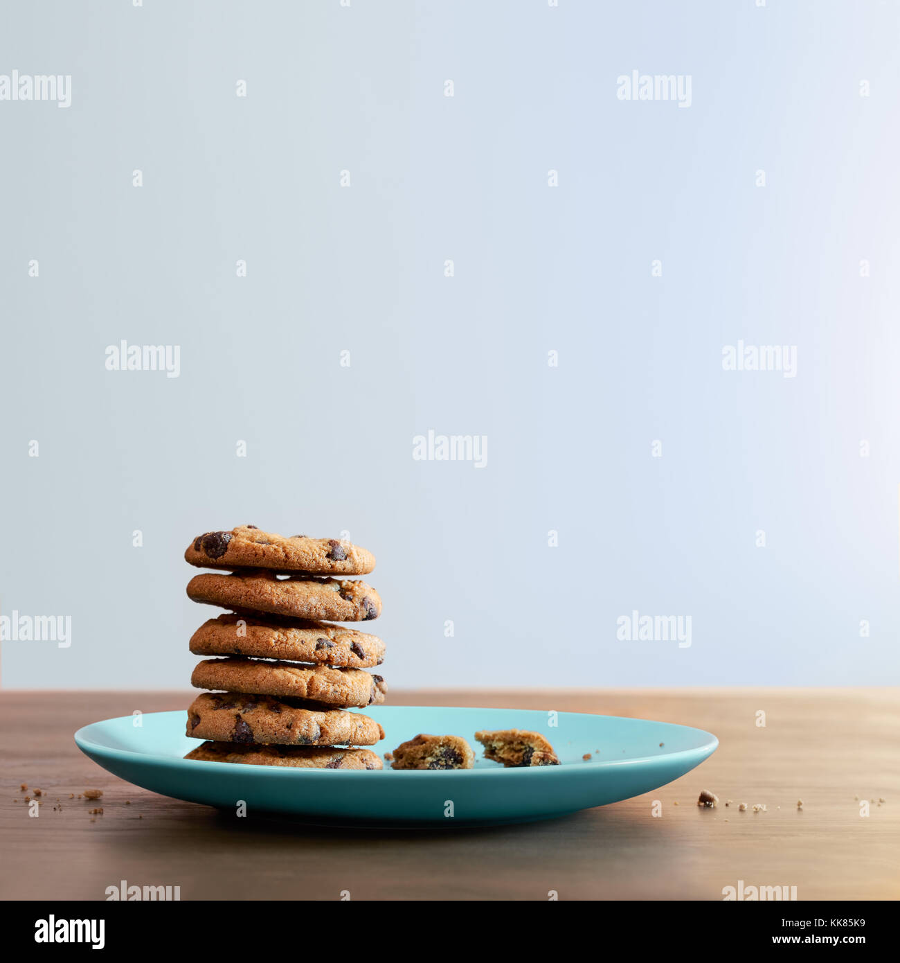 Warm chocolate chip cookies and stacked on a plate with crumbs on old