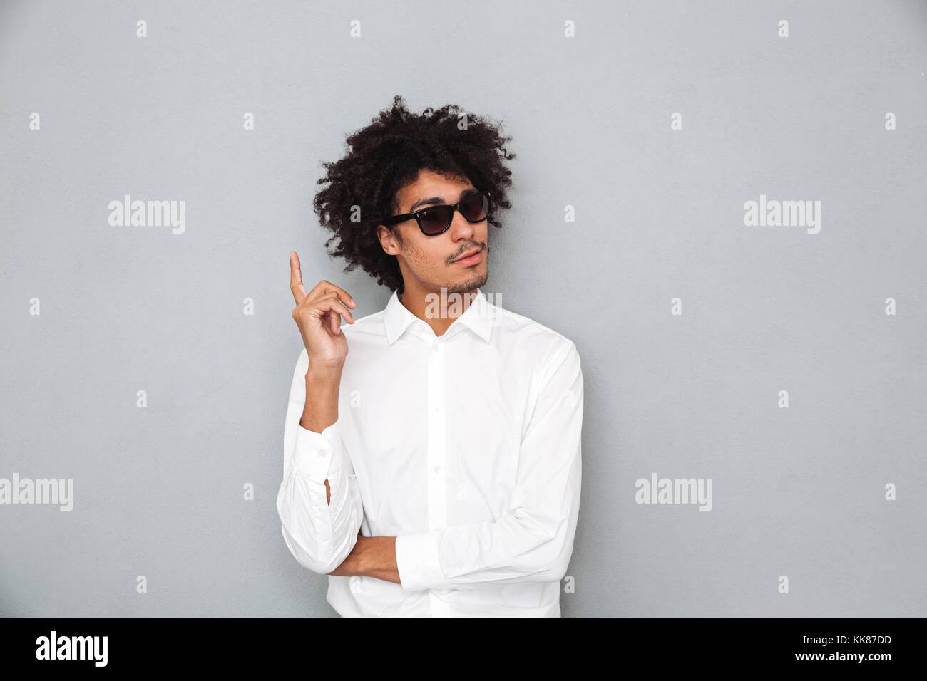 Portrait of a successful young african man in white shirt pointing ...