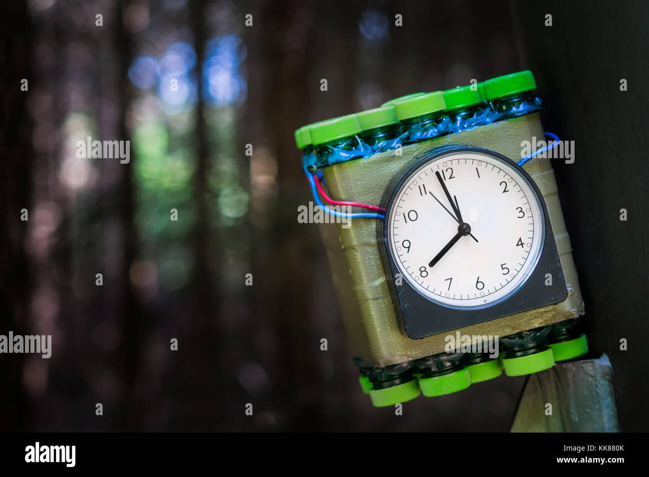 Imitation of timed bomb. Terrorist attack concept. Dangerous explosive placed at metal construction with bokeh background. Stock Photo