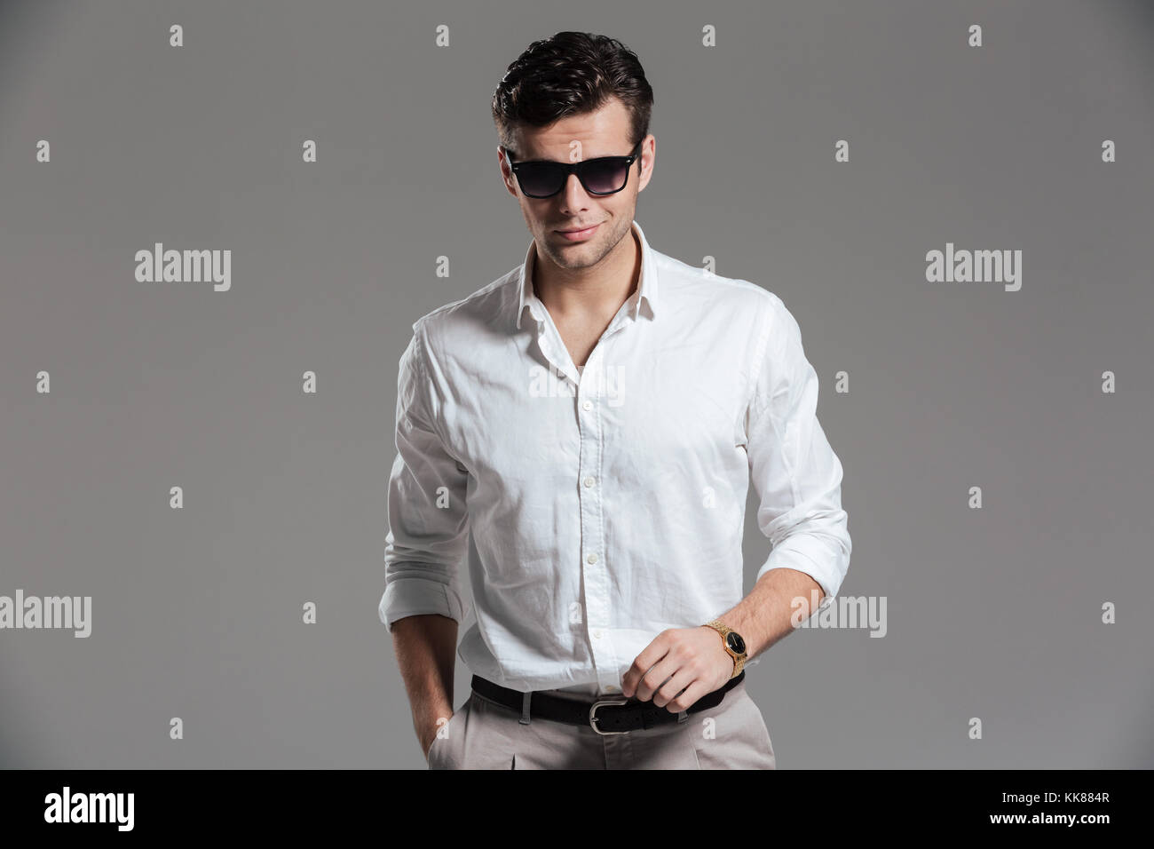 Portrait of a confident young man dressed in white shirt wearing ...