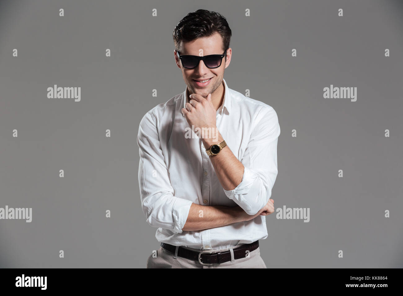 Portrait of a confident smiling man dressed in white shirt wearing ...
