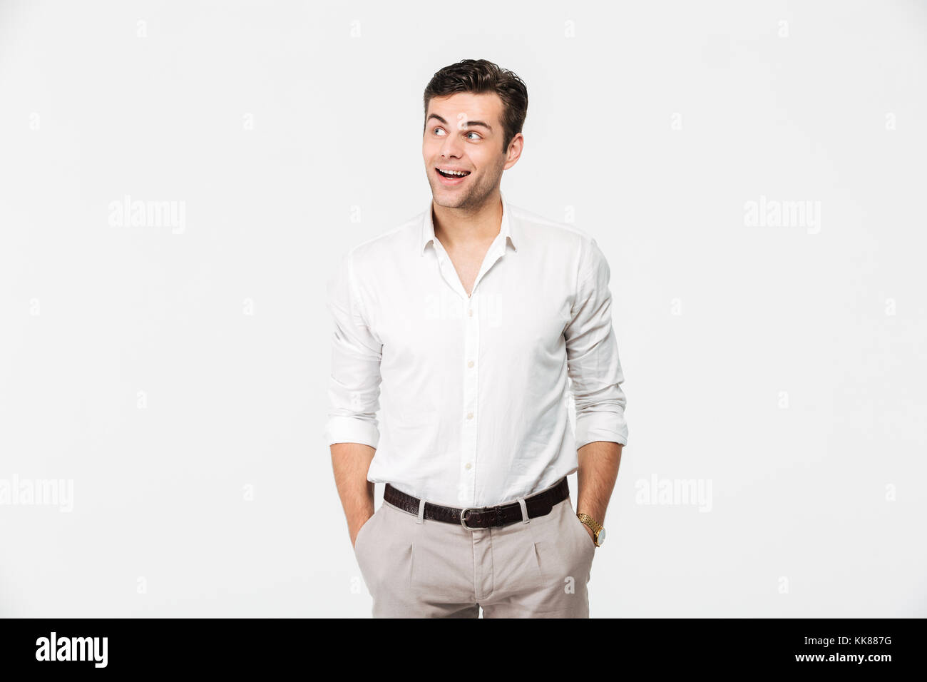 Portrait of a cheerful young man in white shirt standing and looking ...