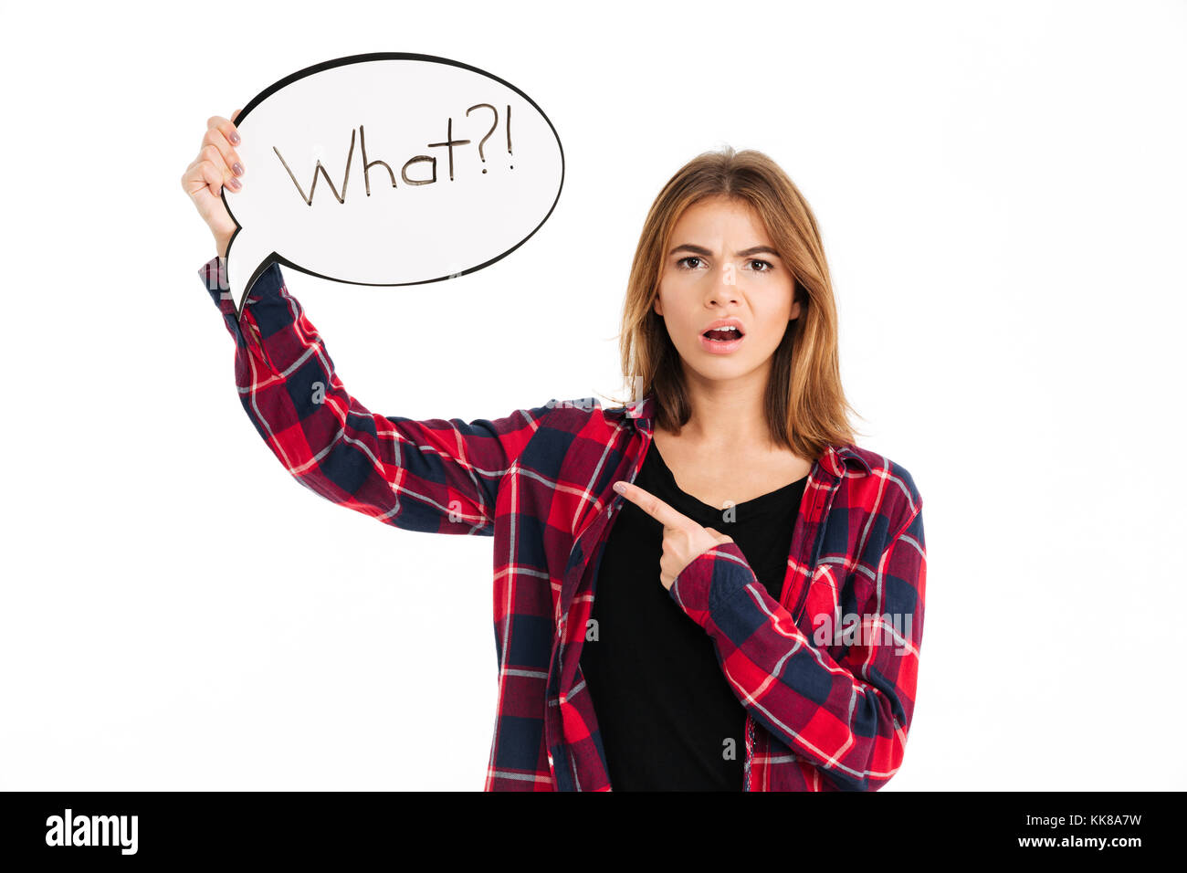 Portrait of a confused frustrated girl holding speech bubble and pointing finger isolated over white background Stock Photo