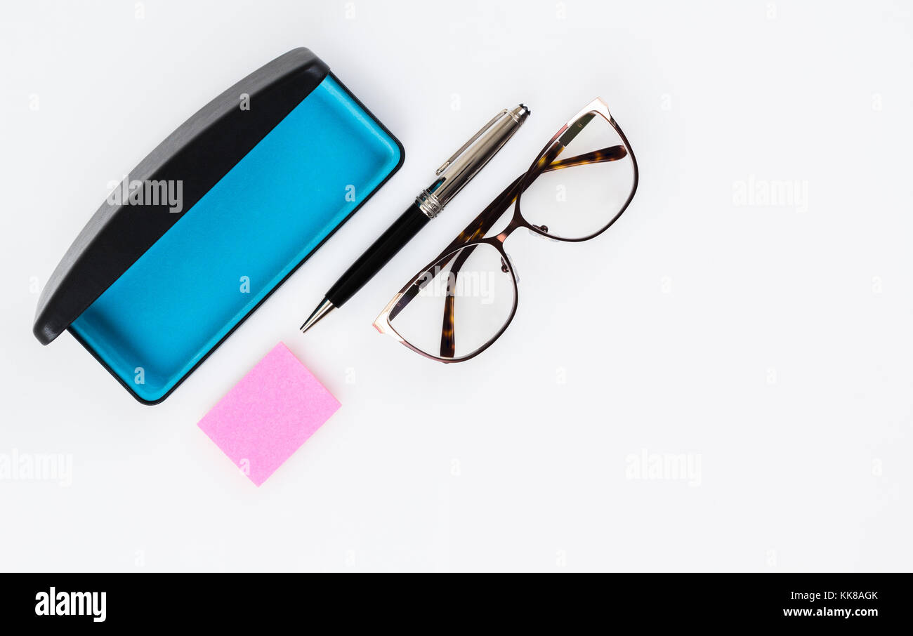 Flat lay eyeglasses, sticky note pad and fancy pen on white background