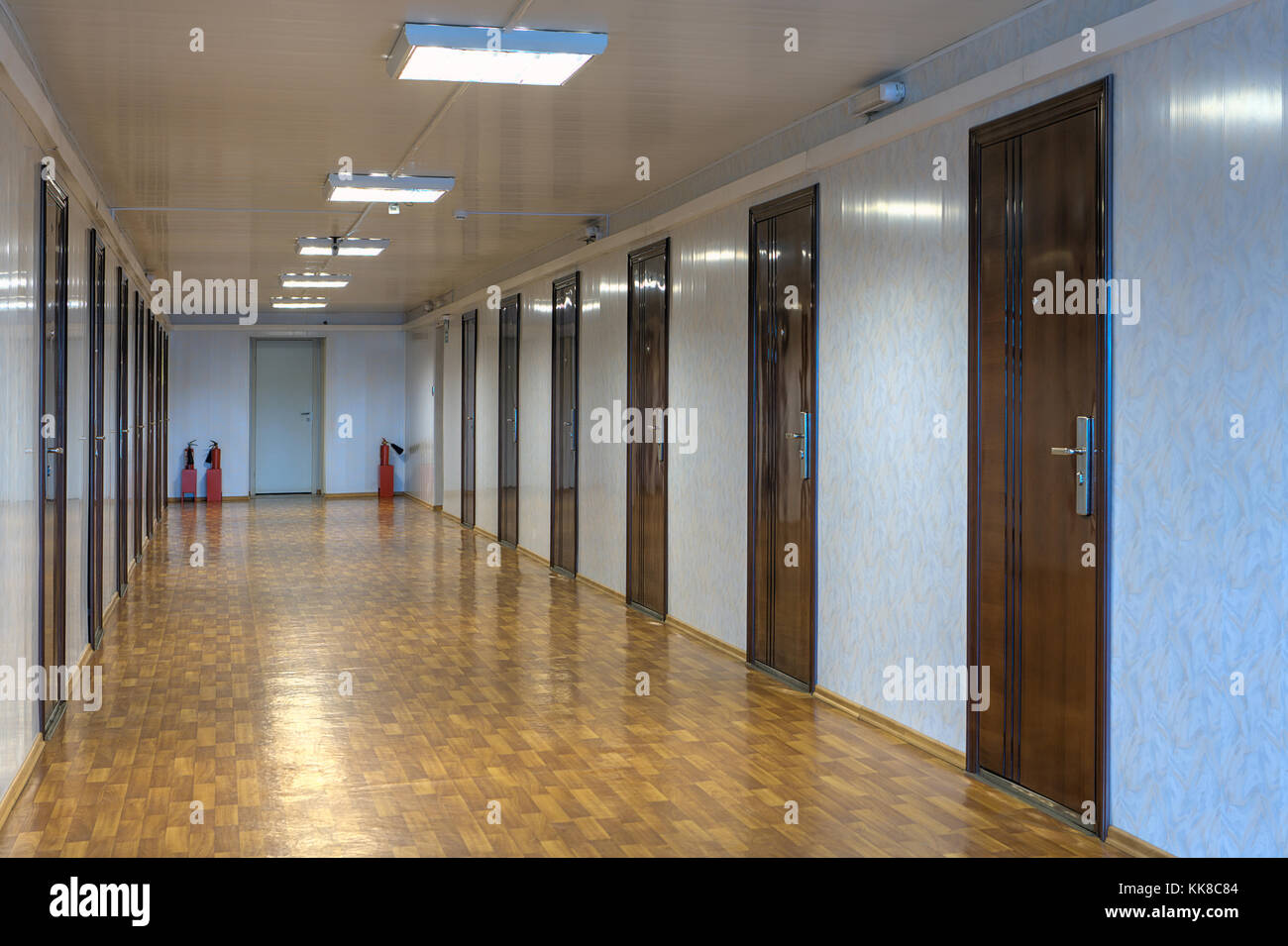 Long Office Hallway With Many Doors Of Dark Red Wood Stock