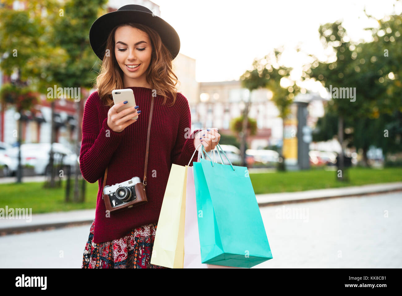 Portrait of a cheerful smiling girl with retro camera holding shopping ...