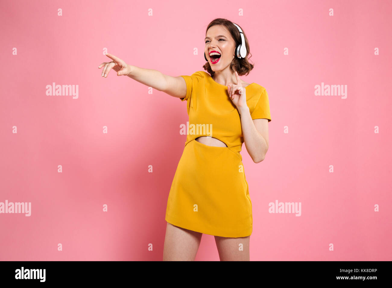 Close-up portrait of happy young woman in yellow dress and headphones ...