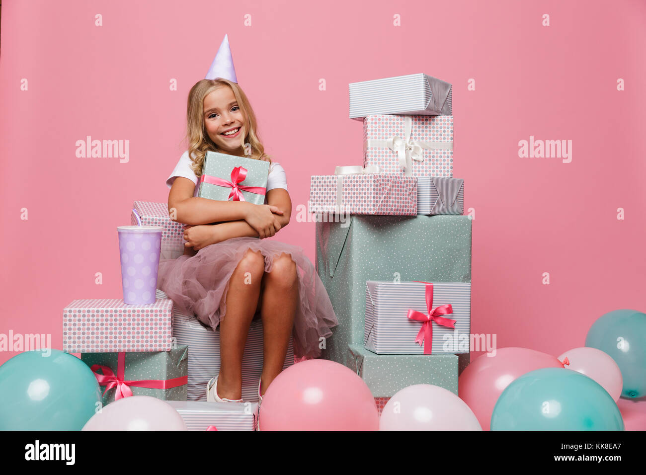 Portrait of a happy pretty little girl in a birthday hat celebrating ...