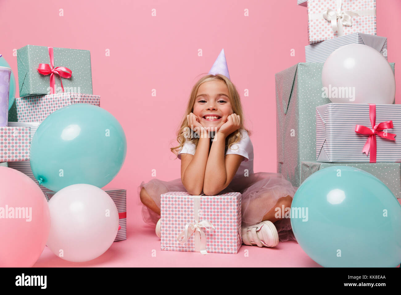 Portrait of a happy pretty little girl in a birthday hat celebrating ...