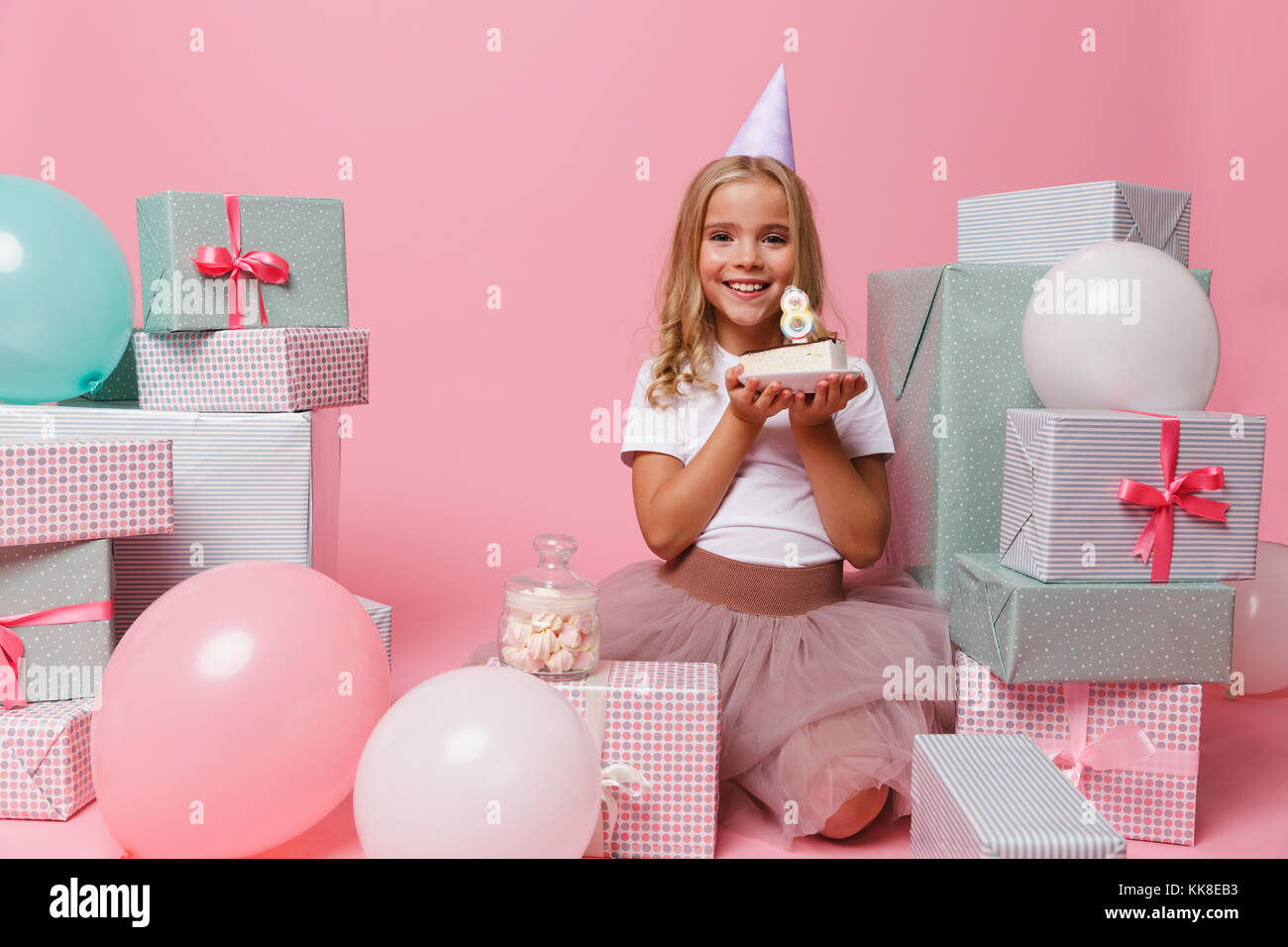 Portrait of a smiling pretty little girl in a birthday hat celebrating ...